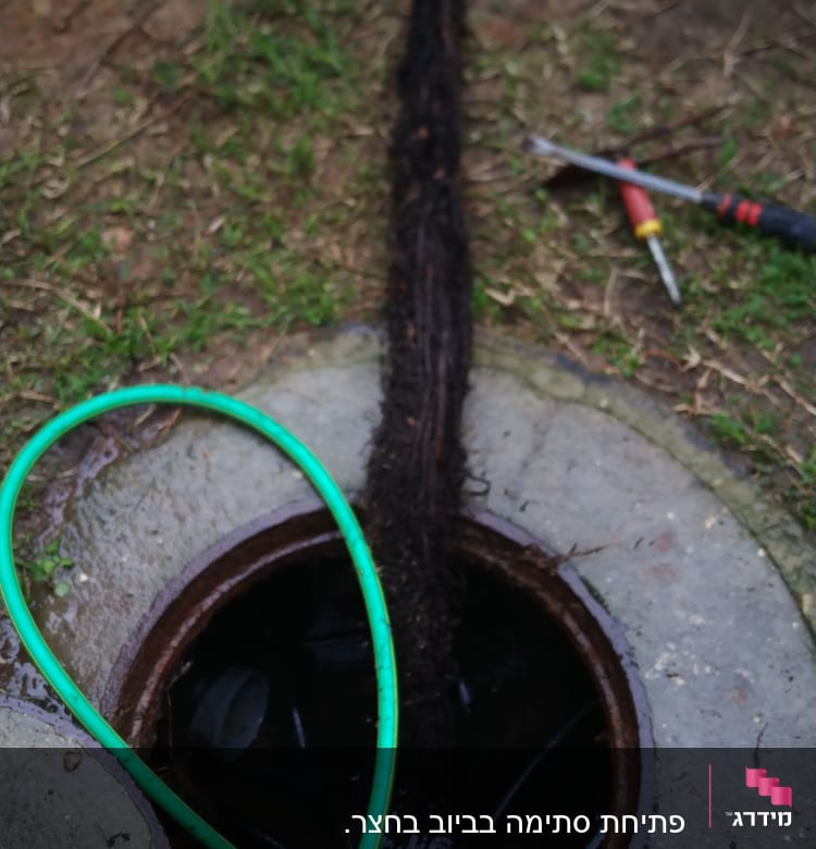 צינור ירוק וכלי עבודה ליד פתח ביוב